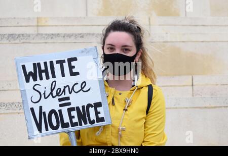 Eine junge kaukasische Frau protestiert bei einer britischen Anti-Rassismus-Kundgebung in Großbritannien mit einem Schild mit der Aufschrift "White Silence equals Violence" Stockfoto