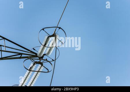 Nahaufnahme eines elektrischen Hochspannungsisolators aus Glas, einer Stromleitung an einem klaren blauen Himmel Stockfoto