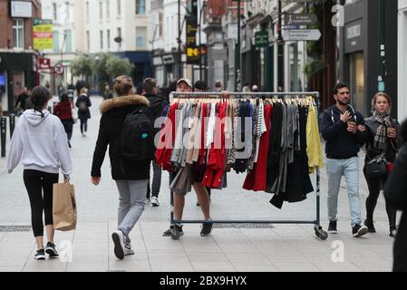 Ein Mann rollt ein Kleidergestell in der Grafton Street in Dublin entlang, da die zweite Phase der irischen Coronavirus-Rückgewinnungsfahrkarte wie geplant am Montag beginnt, zusammen mit anderen Maßnahmen, die ursprünglich für spätere Phasen vorgesehen waren. Stockfoto