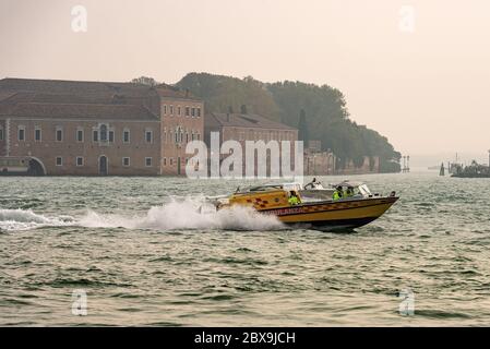 Der Wasserwagen (kleines Motorboot) fährt schnell für einen Notfall in der venezianischen Lagune (Canale della Giudecca) mit vier Personen an Bord. Venedig, Venetien Stockfoto