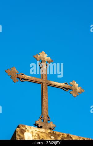 Nahaufnahme eines alten christlichen Kreuzes in Schmiedeeisen auf einem klaren blauen Himmel mit Kopie Raum, religiöse Symbol. Stockfoto