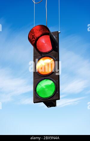 Ampel an einem blauen Himmel mit Wolken, mit allen drei Lichter an, grün, orange und rot. Stockfoto