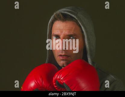 Nahaufnahme Gesicht Porträt von jungen attraktiven und wild aussehenden Mann in Boxhandschuhen posiert in Verteidigung Boxer Haltung isoliert auf dunklem Hintergrund im Sport Stockfoto