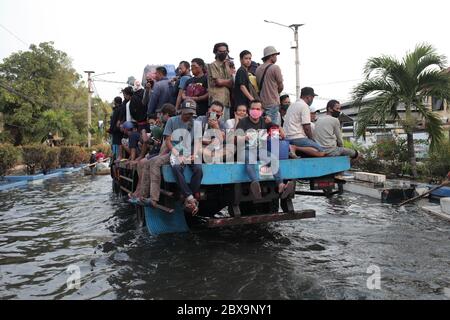 Jakarta, Indonesien. Juni 2020. Ein LKW mit Menschen beladen fährt durch eine raubenüberflutete Straße in Jakarta.Rob überschwemmt in Jarkata, dies ist ein Phänomen, wo das Meerwasser ins Festland überfließt. Es kann auch als eine Pfütze von Wasser auf Küstenland interpretiert werden, die auftritt, wenn die Gezeitengewässer hoch sind und somit Teile der Küstenebene überschwemme. Quelle: SOPA Images Limited/Alamy Live News Stockfoto