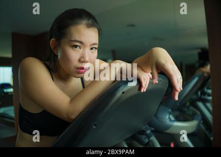 Junge attraktive und fit asiatische chinesische Frau erschöpft während des Lauftrainings im Hotel-Fitnessstudio oder Fitness-Club Joggen im Laufband hart mit tir Stockfoto
