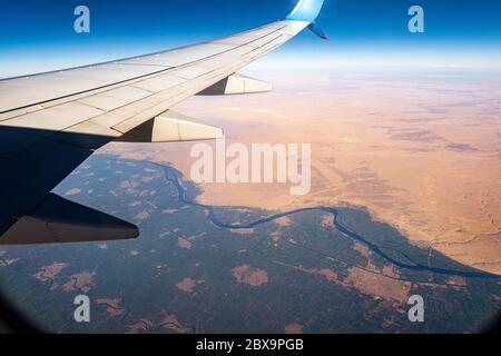 Sahara-Wüste und der Nil vom Flugzeug mit dem Flugzeugflügel mit der Stadt Mallawi, Minya Governorate, Ägypten, Afrika Stockfoto