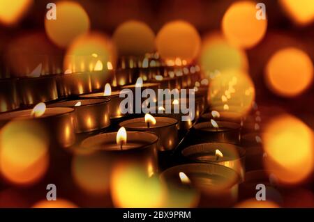 Nahaufnahme einer Gruppe von Votivkerzen, Teelampen, mit Bokeh-Effekt. Warmer Hintergrund Stockfoto