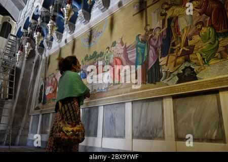 Ein Besucher sieht ein Wandmosaik, das den Körper Jesu Christi darstellt, der nach seinem Tod vorbereitet wird, gegenüber dem Salbungsstein in der Grabeskirche in der Altstadt von Ostjerusalem Israel Stockfoto