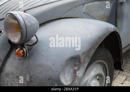 Vorne mit Scheinwerfer und einer Delle im Kotflügel eines alten heruntergekommenen Autos (Citroen 2CV) im Dorf Raerd, Niederlande Stockfoto