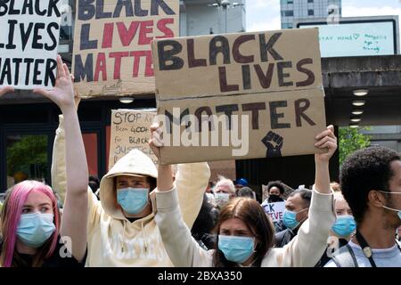 Schwarze Leben Materie Protest Manchester UK. Demonstranten, die Gesichtsmasken tragen, halten Schild hoch. Im Hintergrund wird die Meldung Stay Home angezeigt Stockfoto