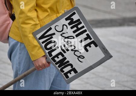 Eine junge kaukasische Frau protestiert bei einer britischen Anti-Rassismus-Kundgebung in Großbritannien mit einem Schild mit der Aufschrift "White Silence equals Violence" Stockfoto