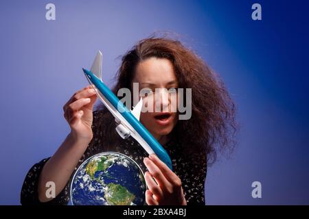 Mädchen mit einem Flugzeugmodell in den Armen über einem Erdball. Konzept der Airline Hilfe. Stockfoto