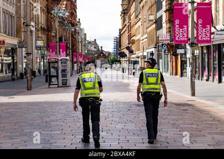 Glasgow, Schottland, Großbritannien. Juni 2020. Normalerweise geschäftiges Einkaufsviertel der Buchanan Street im Stadtzentrum von Glasgow ist an einem Samstagmittag fast menschenleer. Geschäfte und Geschäfte bleiben geschlossen und in vielen Fällen verladen. Polizei Patrouille leere Buchanan Street Fußgängerzone. Iain Masterton/Alamy Live News Stockfoto