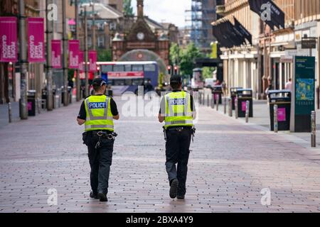 Glasgow, Schottland, Großbritannien. Juni 2020. Normalerweise geschäftiges Einkaufsviertel der Buchanan Street im Stadtzentrum von Glasgow ist an einem Samstagmittag fast menschenleer. Geschäfte und Geschäfte bleiben geschlossen und in vielen Fällen verladen. Polizei Patrouille leere Buchanan Street Fußgängerzone. Iain Masterton/Alamy Live News Stockfoto