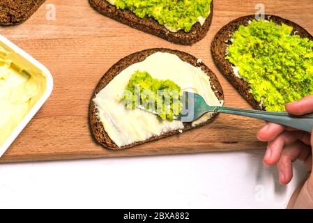 Avocado-Püree auf einer Gabel. Avocado-Toast. Vegetarisches Rezept. Eine Draufsicht auf ein flaches Layout. Stockfoto