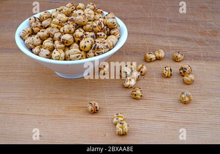 Plateful von Bio gerösteten würzigen Kichererbsen und verschütteten Kichererbsen auf Holzhintergrund Stockfoto