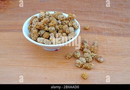 Plateful von Bio getrocknete Maulbeere und verschüttete getrocknete Maulbeere auf Holzhintergrund Stockfoto