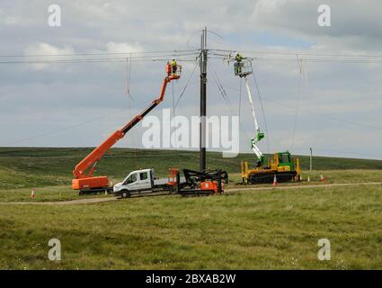 Linienzüge auf mobilen Hocharbeitsbühnen, die eine neue 132 kV elektrische Freileitungsverbindung zu einem windfarm.in Dumfries und Galloway bauen Stockfoto