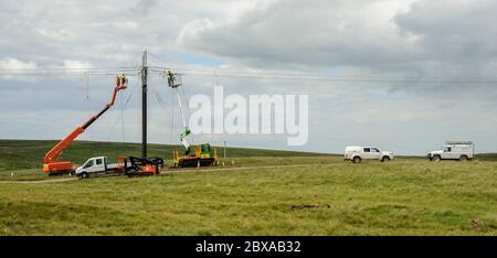 Linienzüge auf mobilen Hocharbeitsbühnen, die eine neue 132 kV elektrische Freileitungsverbindung zu einem windfarm.in Dumfries und Galloway bauen Stockfoto