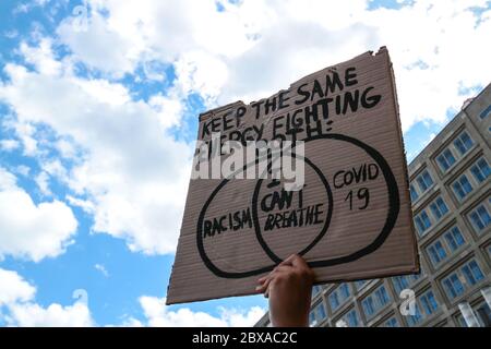 Protestschild liest Kreuzung 'Rassismus - ich kann nicht atmen - covid 19' bei einem Black Lives Matter Protest Alexanderplatz Berlin, Deutschland. Stockfoto