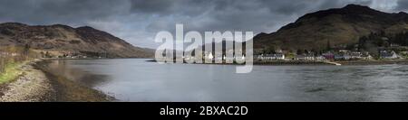 Panoramablick auf Dornie Dorf über Loch Long mit bewölktem Himmel und lückenhaft Sonnenlicht auf das Dorf und die Küste Stockfoto