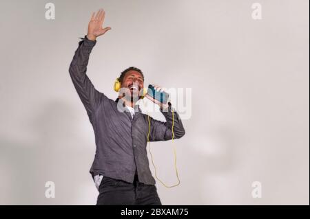 Natürliches Porträt der 40er Jahre glücklich und aufgeregt attraktiver Mann hören Online-Musik mit Kopfhörern und Handy singen Lied und tanzen sorglos ist Stockfoto