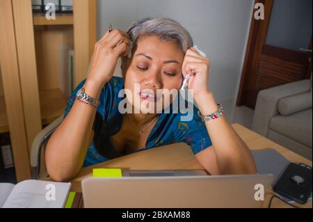 Ausdrucksstarkes Porträt der attraktiven gestressten und überarbeiteten asiatischen Frau, die am Büro Laptop Computer Schreibtisch im Stress arbeitet, frustriert und aufgeregt Stockfoto