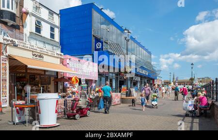 Menschen, die an Geschäften und einer Spielhalle an der Promenade in Bridlington, East Yorkshire, vorbeilaufen Stockfoto