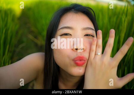 Junge glücklich und schöne asiatische Frau, die Selfie Foto im Freien zeigt stolz ihr Verlobungsring. Fröhlich koreanisches Mädchen als Verlobter unter sich selbst portr Stockfoto