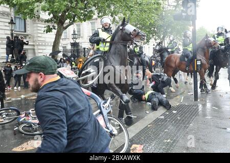 Ein verletzter Polizist wird nach einer Polizeigebühr auf dem Pferderücken Gebühr in Whitehall nach einer Protestkundgebung Black Lives Matter auf dem Parliament Square, London, in Erinnerung an George Floyd, der am 25. Mai während in Polizeigewahrsam in der US-Stadt Minneapolis getötet wurde, geneigt. Stockfoto