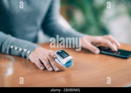 Ältere Frau, die zu Hause Pulsoximeter verwendet Stockfoto