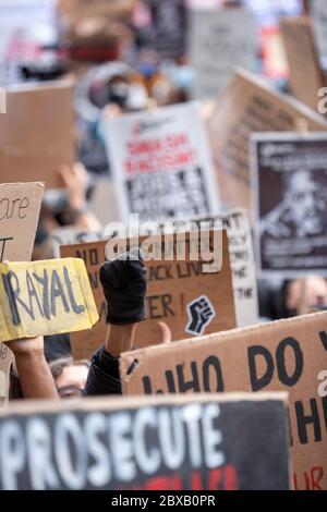 Eine aufgezogene, mit Handschuhen beklagt Faust ragt in einem Meer von selbstgemachten Kartonschildern hervor, bei der Black Lives Matter UK Protest, Parliament Square, London, England, UK Stockfoto