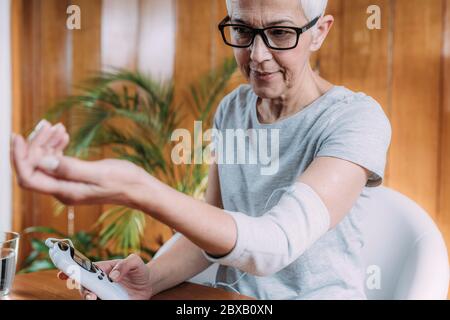 Ältere Frau macht Ellbogen Physiotherapie mit TENS Stockfoto