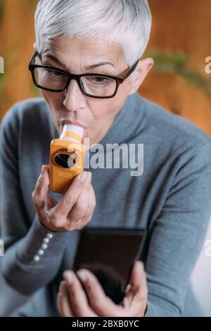 Ältere Frau, die zu Hause Spirometer verwendet Stockfoto