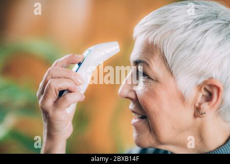 Körpertemperatur mit berührungslosem Thermometer messen Stockfoto