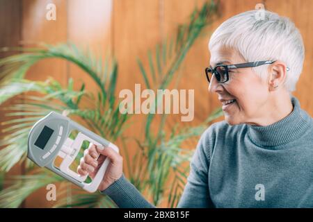 Ältere Frau mit digitalem Handgriff Kraftprüfstand Stockfoto