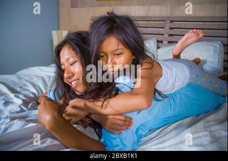 Lifestyle Schlafzimmer Porträt von glücklichen asiatischen Frau zu Hause spielen mit kleinen Tochter im Bett Kuscheln und lachen fröhlich in Mutter und Kind Liebe ein Stockfoto