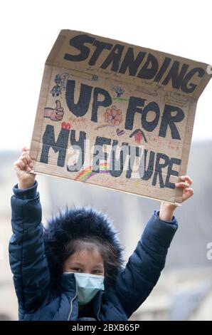 Das junge Mädchen trägt eine chirurgische Gesichtsmaske und einen pelzigen Kapuzenmantel und hält beim BLM UK Protest ein Schild "für meine Zukunft aufstehen" hoch. London, Großbritannien Stockfoto