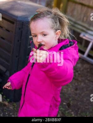 Corona Kompostierung, 4 Jahre altes Mädchen vor der Schule Entleeren der Komposteimer, immer Ihr Kind interessant im Garten. Corona Lockdown Gartenarbeit Stockfoto