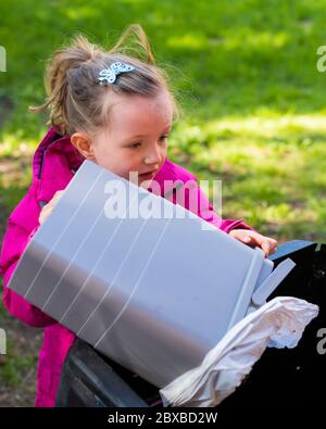 4-jähriges Mädchen, das den Kompostbehälter entleert, Ihr Kind in der Gartenarbeit interessant macht, Vorschulkinder lernen, den Kompostbehälter zu leeren Stockfoto