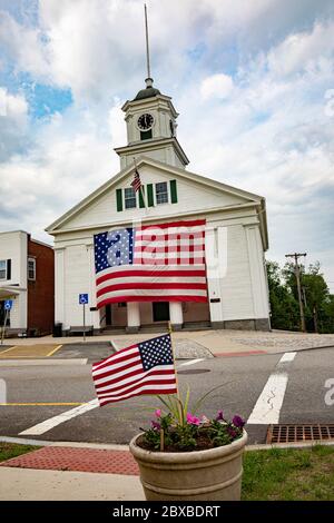 Das Barre, Massachusetts Town Hall mit einer sehr großen amerikanischen Flagge, die an der Vorderseite des Rathauses hängt. Stockfoto