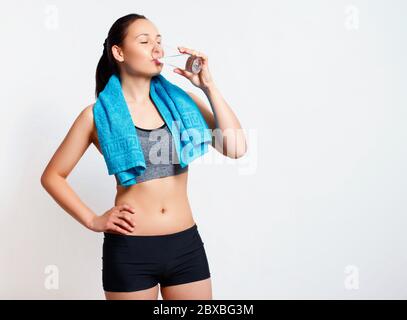 Frau nach dem Training trinkt Wasser aus einem Glas. Auf weißem Hintergrund. Stockfoto