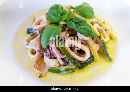 Tintenfisch und Zucchini bereit zu essen. Tintenfisch in Kreise geschnitten und in einer Pfanne mit Zucchini, Olivenöl und Basilikum gekocht. Italienische Küche Stockfoto