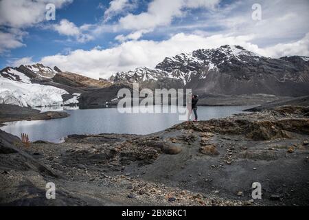 Paar in einem Gletscher, in der Nähe eines Sees, Berge mit Schnee in ihren Gipfeln, Wolken und blauen Himmel Stockfoto