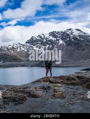 Paar in einem Gletscher, in der Nähe eines Sees, Berge mit Schnee in ihren Gipfeln, Wolken und blauen Himmel Stockfoto