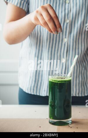 Junge Frau mit gesunden Gewohnheiten bereitet einen Gemüsesaft mit Sesam zu Stockfoto