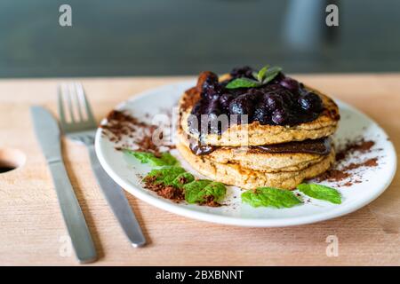 Köstliche Hafer amerikanische Pfannkuchen mit hausgemachten Schokolade Belag, gekochte Heidelbeeren und frische Minzblätter. Gesundes Kochen im Lebensstil Stockfoto