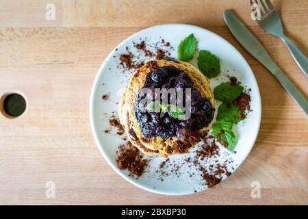 Köstliche Hafer amerikanische Pfannkuchen mit hausgemachten Schokolade Belag, gekochte Heidelbeeren und frische Minzblätter. Gesundes Kochen im Lebensstil Stockfoto