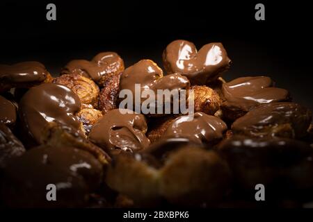 Schokolade palmier Kekse low light. Herzförmiges Blätterteig, Schweinehaar, Palmenblätter-Kekse, Elefantenohren, französische Herzen, Schuhsohlen. Stockfoto