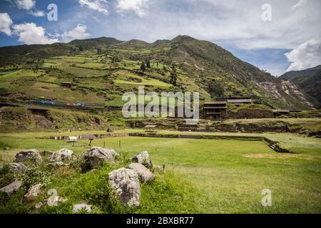 Landschaft, große grüne Berge, Bäume und kleine Hütten, Wolken und blauer Himmel Stockfoto